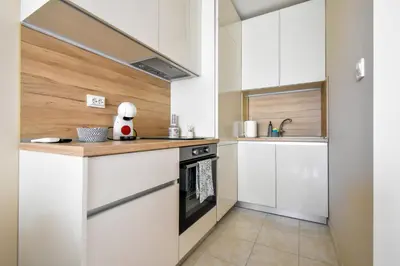a small kitchen with white cabinets and a stove at Sunny Sofia Studio with Balcony by Flat Mаnager in Sofia