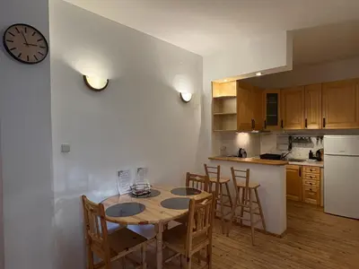 a kitchen with a table and chairs and a clock on the wall at Charming Loft Sofia Center in Sofia