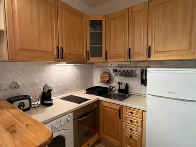 a kitchen with wooden cabinets and a white refrigerator at Charming Loft Sofia Center in Sofia