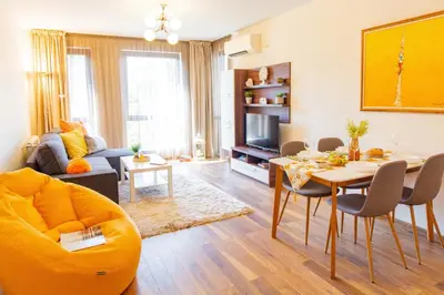 a living room with a yellow couch and a table at Domus Apartment Amber with Parking in Plovdiv