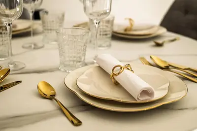 a table with a plate with a napkin and gold spoons at Einik Luxury Apartments in Velingrad