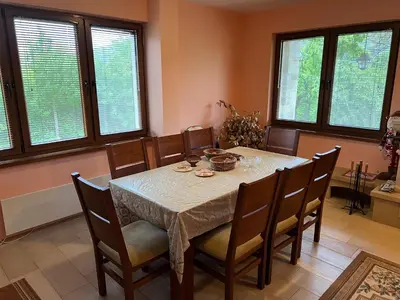 a dining room with a table and chairs and windows at The Old Walnut House in Terziysko