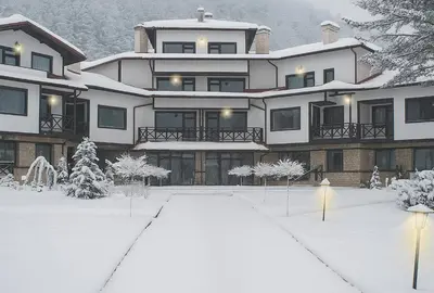 a large white house with snow on the ground at Everwood Hotel & Restaurant in Govedartsi