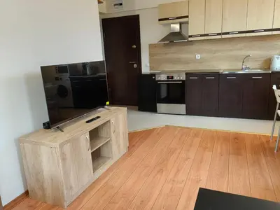 a large kitchen with wooden cabinets and a wooden floor at Апартамент Мария in Bansko