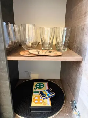 a shelf with glasses and a book on a plate at Madzharovi Apartments in Borovets
