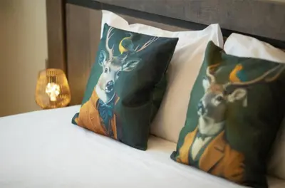 a bed with two pillows with a painting of a deer at Madzharovi Apartments in Borovets