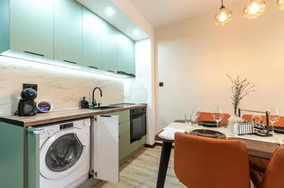 a kitchen with a washing machine and a table with chairs at Vutovi's corner made with care 2 in Bansko