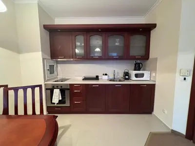 a kitchen with wooden cabinets and a microwave at Downtown Bansko Resort in Bansko