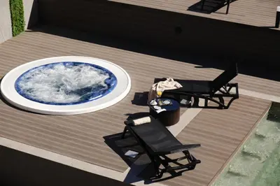 a deck with a pool and two chairs and a table at Comfy 1bd apartment in 4star SPA resort Bansko in Bansko