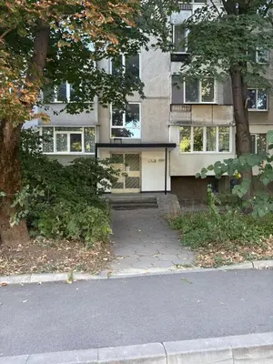 a house with a black roof in front of a building at ApartSofiaMusagenica in Sofia