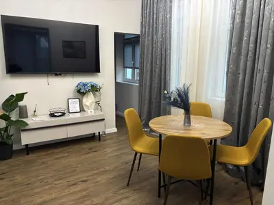 a living room with a table and yellow chairs at Kapana by V2 in Plovdiv