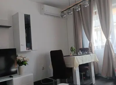 a living room with a table and a window at Double next to NBU and Merto station, free parking in Sofia