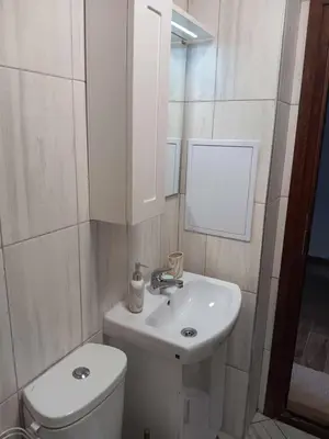 a white bathroom with a toilet and a sink at Double next to NBU and Merto station, free parking in Sofia