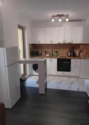 a kitchen with white cabinets and a white table at Double next to NBU and Merto station, free parking in Sofia