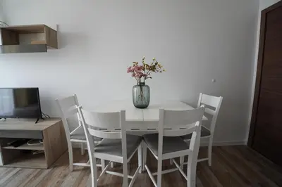 a white dining room table with a vase of flowers on it at Cozy place with free parking in Sofia