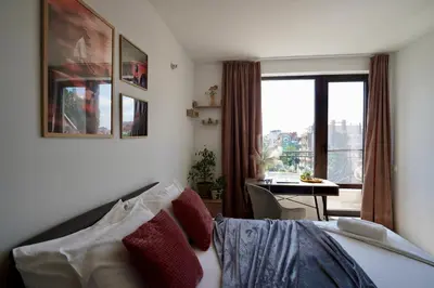 a bedroom with a bed and a table and a window at Cozy place with free parking in Sofia