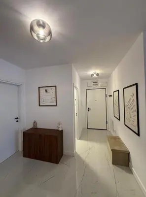a white hallway with a bench and a door at Modern 2 Bedroom - 2 Baths - Private Garage Free in Center in Sofia