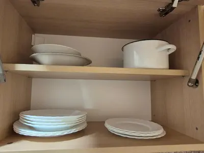 two plates and bowls on shelves in a kitchen at Mladost stay apartment in Sofia