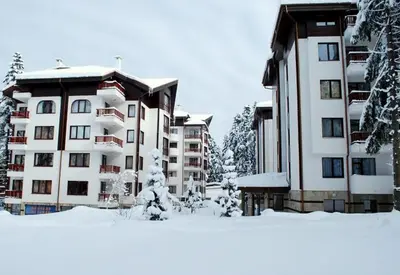 a building with snow on the ground in front of it at Private apartments in Flora Residence in Borovets