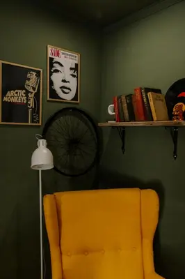 a room with a yellow chair and a shelf with books at Villa YASNA - Art of slow living in Sredno Gradishte