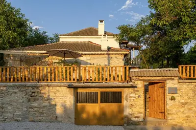 a building with a wooden deck and an umbrella at Villa YASNA - Art of slow living in Sredno Gradishte