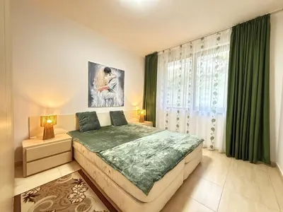 a bedroom with a large bed and green curtains at Apartment Grand Monastery Pamporovo in Pamporovo