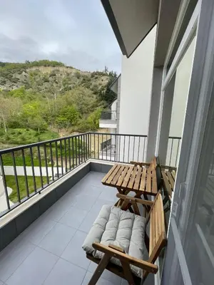 a balcony with a wooden table and chairs on it at Well Equipped New Family Friendly One-Bedroom Flat in Sandanski