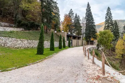 a gravel road with trees and a stone wall at Villa Rossa Luxury & Spa Residence in Narechenski Bani