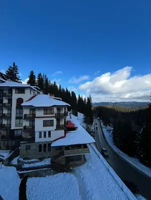 a building covered in snow next to a road at Cedar Heights 1 Виванко А7 in Pamporovo