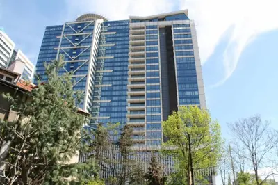 a tall glass building with trees in front of it at cosy apartment in Sofia