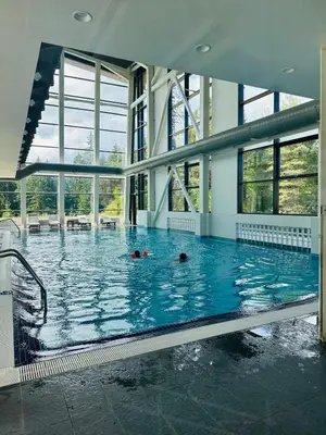 a large swimming pool with two people swimming in it at White & Wood Suite C302, at Euphoria SPA Borovets in Borovets