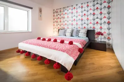 a bedroom with a bed with red flowers on it at Alexandra's City Center Apartment I in Sofia