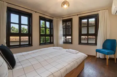 a bedroom with a bed and a blue chair and windows at Blue House in Plovdiv