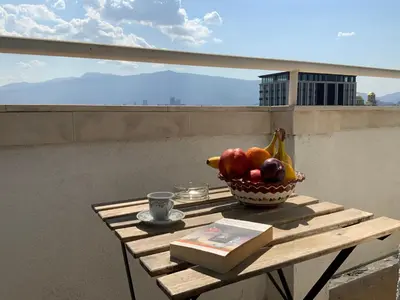 a bowl of fruit and a book on a table at Zaimov Penthouse with great view in Sofia