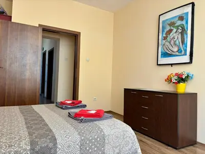 a bedroom with a bed and a dresser and a painting at Comfy Apt next to Palace of Justice in Sofia