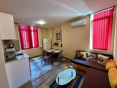 a kitchen and a living room with a couch and a table at Comfy Apt next to Palace of Justice in Sofia
