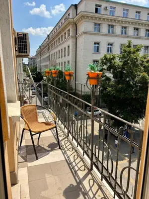 a balcony with a table and a chair and a building at Comfy Apt next to Palace of Justice in Sofia