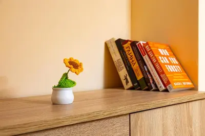 a flower in a vase on a shelf with books at Sunflower Studio next to Kolodrum Plovdiv in Plovdiv