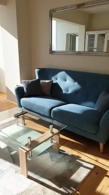 a blue couch in a living room with a mirror at Sunny and Charming Domain for Your Stay in Sofia in Sofia