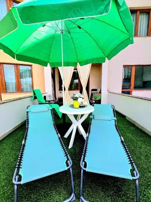 a table and two chairs with a green umbrella at Apartment - Studio Cucetno in Sandanski