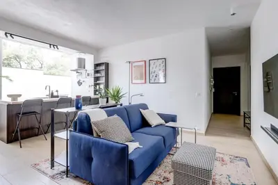a living room with a blue couch and a kitchen at Modern 1BDMApartment Near Shopping Mall & Metro in Sofia