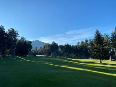 a golf course with trees and a green field at Pirin Golf Cozy Mountain Apartment with Views of Pirin & Rila in Bansko