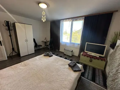 a living room with a large bed and a television at Mountain Whisper Guesthouse in Smolyan