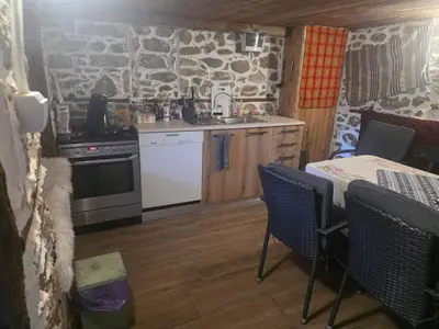 a kitchen with a stove and a table and chairs at Mountain Whisper Guesthouse in Smolyan