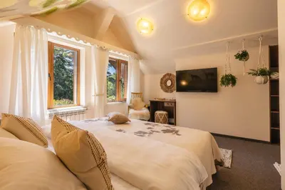 a bedroom with two beds and a tv on the wall at Хижа Кукер - Арт Хижа за Вдъхновение и Отдих in Sofia