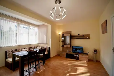 a living room with a table and a couch and a chandelier at Apartment near a Metro Station in Sofia