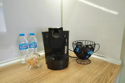 a coffee maker on a wooden floor with bottles of water at Apartment near a Metro Station in Sofia