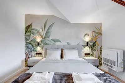 a bedroom with a large white bed with plants on the wall at City Gem 1BDRM 200m Sofia Statue in Sofia