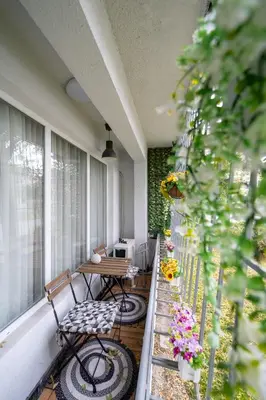 a porch with two chairs and a table and flowers at Бизнес & Арт апартамент - до Панаира и Капана in Plovdiv