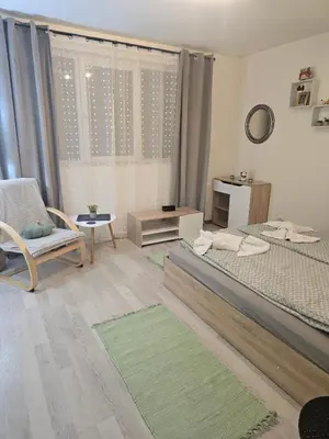 a bedroom with two beds and a chair and a window at Peshtera Cozy Apartment in Peshtera